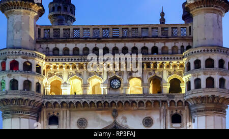 Eine Nahaufnahme der Fassade und die Uhr der Charminar, "vier Minarette", in der Dämmerung. Die Innenräume des Denkmals in Hyderabad, Indien, leuchtet die Lichter. Stockfoto