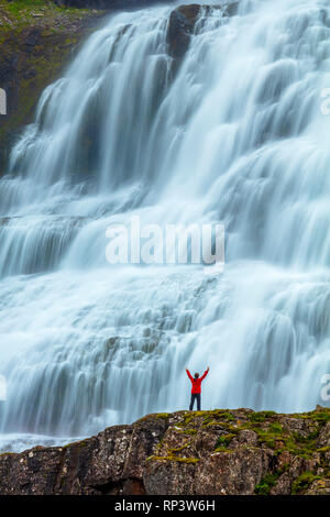 Person durch Dynjandi Wasserfall, oder Fjallfoss, Westfjorde, Island in den Schatten gestellt. Stockfoto