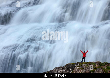 Person durch Dynjandi Wasserfall, oder Fjallfoss, Westfjorde, Island in den Schatten gestellt. Stockfoto