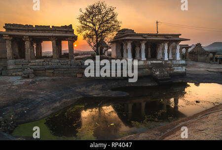 Hampi karnakata Indien Tempel und Silhouette Baum am Sunset Point bunte Himmel und Reflexion in einem kleinen See Stockfoto