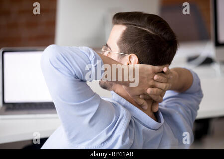 Serene Arbeiter am Schreibtisch sitzen hält die Hände hinter dem Kopf entspannen im Büro. Mitarbeiter fertigen Arbeit fühlt sich gerne frische Luft geniessen Brak Stockfoto