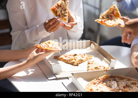 Diverse Mitarbeiter und Kollegen in Pause genießen Sie Corporate Lunch essen Pizza im Büro zusammen, Nahaufnahme, Hände von Geschäftsleuten. Ungesunde schnelle foo Stockfoto