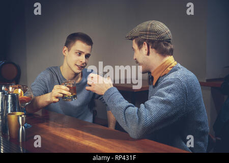 Zwei junge Männer in legere Kleidung sprechen beim Sitzen an der Theke im Pub Stockfoto