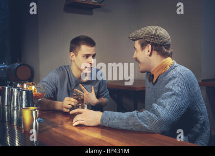 Zwei junge Männer in legere Kleidung sprechen beim Sitzen an der Theke im Pub Stockfoto