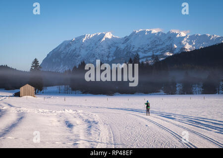 Frau laufen Langlaufen in Bad Mitterndorf mit schöner Aussicht auf die Berge Grimming an einem sonnigen Wintertag in der Steiermark, Österreich Stockfoto