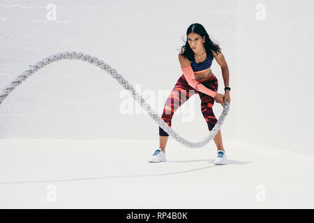 Fitness-Frau, die Krafttraining mit Kampfseil macht. Athletische Frau, die mit Kampfseil trainieren muss. Stockfoto