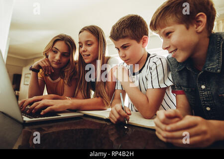 Jungen und Mädchen sitzen zu Hause studieren zusammen auf einem Laptop. Kinder lernen auf einem Computer mit großem Interesse. Stockfoto