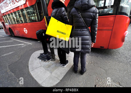 London, England, UK. Frau mit einem Selfridges Tragetasche Überqueren der Straße in Parliament Square Stockfoto