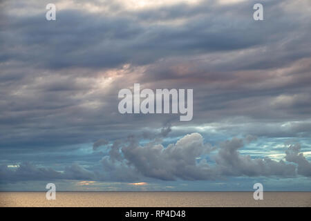 Bunte Wolken über dem ruhigen Meer bei Sonnenuntergang. Stockfoto