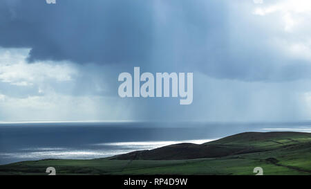 Heavy Rain über ruhige Meer im Hintergrund. Grünen Klippe im Vordergrund. Stockfoto