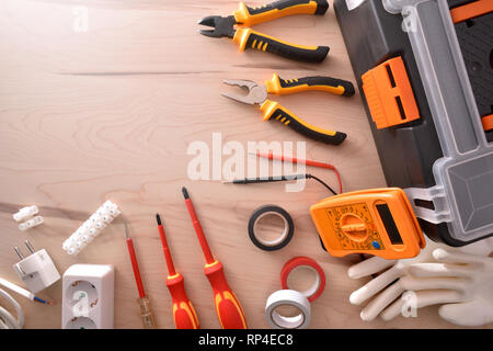 Zusammensetzung der Werkzeuge für elektrische Reparaturen an Holz- Tabelle. Horizontale Komposition. Ansicht von oben. Stockfoto