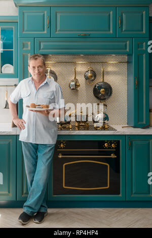 Opa mit Teller von Muffins Stockfoto