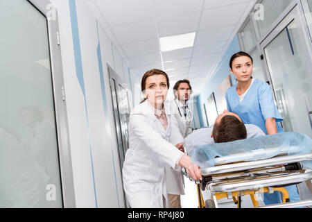 Besorgt, Ärzte und Krankenschwester Transport bewusstlose Patienten auf der Trage Stockfoto