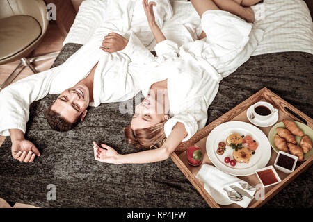 Paar chillen auf dem Bett im Hotel vor dem Frühstück Stockfoto