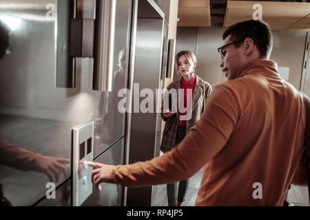 Dunkelhaarige Mann mit orange Polokragen Aufruf der Aufzug Stockfoto