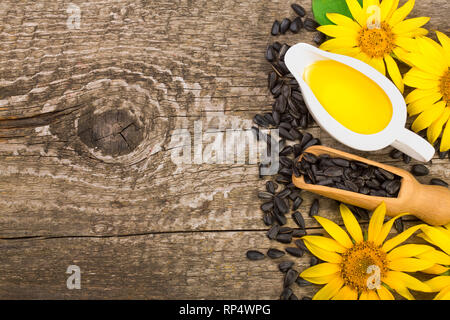 Sonnenblumenöl, Samen und Blüten auf hölzernen Hintergrund mit Kopie Platz für Ihren Text. Ansicht von oben. Stockfoto