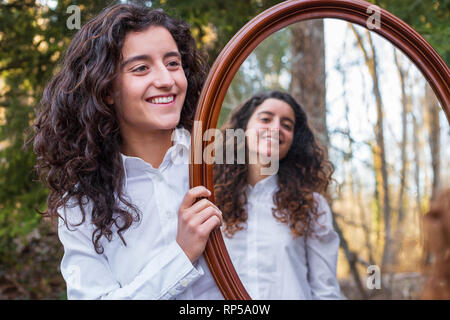 Fröhliche junge Frau, Reflexion der Zwillingsschwester im Herbst Tag im Wald Stockfoto