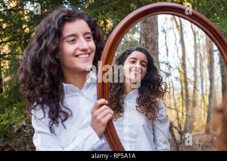 Fröhliche junge Frau, Reflexion der Zwillingsschwester im Herbst Tag im Wald Stockfoto