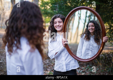 Fröhliche junge Frau, Reflexion der Zwillingsschwester im Herbst Tag im Wald Stockfoto