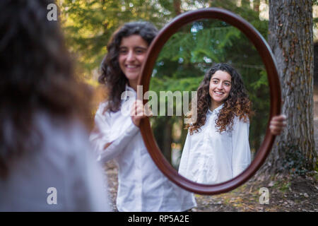 Fröhliche junge Frau, Reflexion der Zwillingsschwester im Herbst Tag im Wald Stockfoto