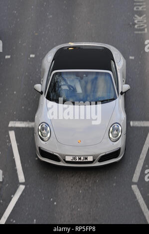 Einen silbernen Porsche 911 Cabrio von oben fotografiert, wie Sie unter einer Brücke fährt. Stockfoto