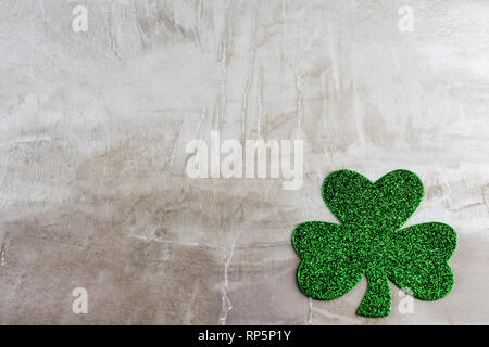 Ein dunkles Grün glitzernde Shamrock in der unteren rechten Ecke. Auf einer tan Steinfliese Hintergrund. Kopieren Sie Platz. Stockfoto