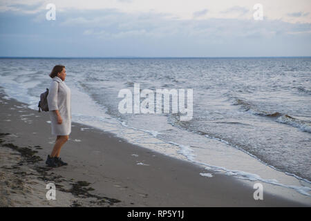 Frau im Mantel Wandern am Meer. Stockfoto