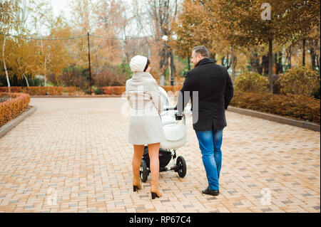 Familie Spaziergang im Herbst Park mit einem Kinderwagen. Mama, Papa und Baby Stockfoto