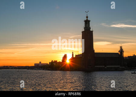 Sonnenuntergang hinter dem Stockholmer Stadshus/Rathaus mit Sonnenstrahlen, Red Sky und eine blaue Wasser von Gamla Stan (Stockholm, Schweden, Europa) Stockfoto