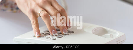 In der breiten Ansicht Bild der weiblichen Hand mit perfekte French Maniküre Wählen einer Telefonnummer mit weißen Festnetztelefon. Stockfoto