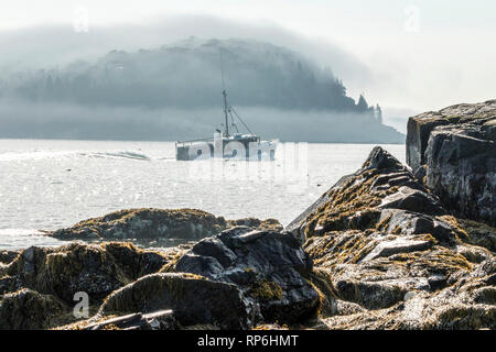 Ein Lobster Boat ist Position von Bar Harbor Maine mit porcupine Insel durch den Nebel im Hintergrund. Stockfoto