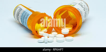 Zwei Verordnungflaschen mit Schmerzen pillen Ausfließen von Ihnen mit einem weißen Hintergrund. Stockfoto