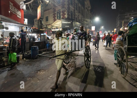 Typische atmosphärischen besetzt in der Nacht laut Zeit Straßenszene in Kolkata mit der lokalen Bevölkerung, Rikschas und Street Food Anbieter. Stockfoto