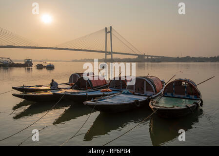 Ein HDR-Ansicht der Vidyasagar Setu Brücke aus Das Prinsep Ghat, die auf dem Hooghly River bei Sonnenuntergang mit touristischen Boote im Vordergrund in Kalkutta. Stockfoto