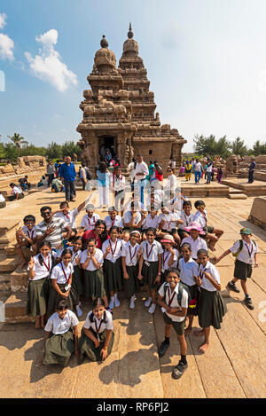 Eine Gruppe von lokalen indischen Schulkinder posieren für die Kamera vor dem Shore Tempel in Mahabalipuram mit Touristen und Einheimischen besucht. Stockfoto