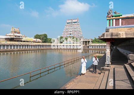 Ein Blick auf die Nordseite gopuram und Teich von Thillai Nataraja Tempel mit 2 Männer beten an einem sonnigen Tag mit blauen Himmel. Stockfoto