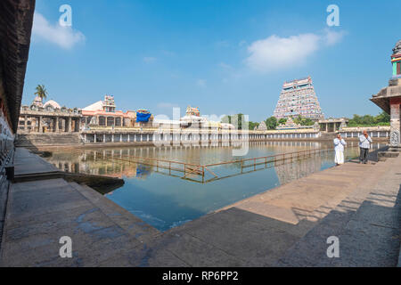 Ein Blick auf die Nordseite gopuram und Teich von Thillai Nataraja Tempel mit 2 Männer beten an einem sonnigen Tag mit blauen Himmel. Stockfoto