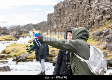 Thingvellir, Island - 20. September 2018: Nationalpark Oxararfoss Wasserfall felsige Landschaft auf Golden Circle mit Wasser Fluss und touristische Paar tak Stockfoto
