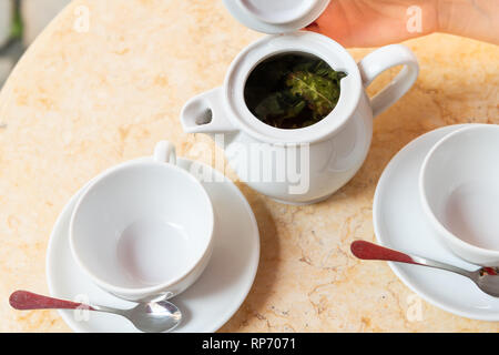 Nahaufnahme von zwei leere weiße Tassen auf Teller untertassen von Grünen oder oolong Tee beim Frühstück Brunch im Cafe Restaurant außerhalb Tabelle mit offenen Teekanne, p Stockfoto