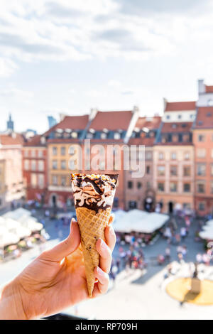 Hand eine weiße Schoko Vanille Eis gelato Kegel mit vertikalen Hintergrund von Warschau, Polen alter Marktplatz historische Gebäude in der Stadt Stockfoto