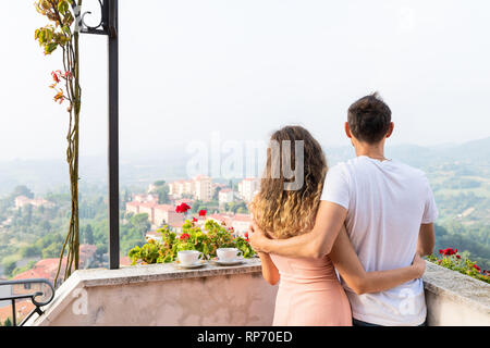 Frau und romantisches Paar Mann auf der Terrasse Garten außerhalb in Italien mit Blick auf die Berge von Chiusi Stadtbild Umbrien nahe der Toskana und Tee oder Kaffee Tassen in Stockfoto