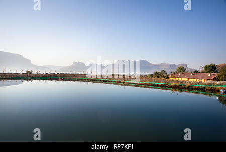 Haus in der Nähe des Stausee im Bergdorf mit rocky mountain Hintergrund in Nasik, Maharashtra, Indien Stockfoto