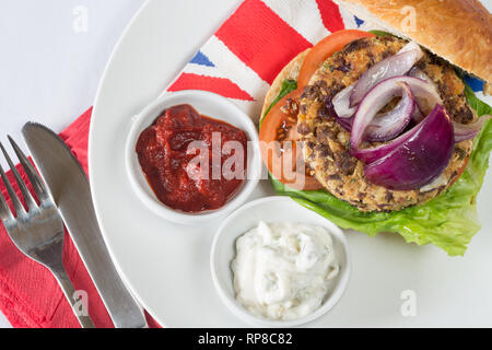 Hausgemachte Quorn Burger in einem sauerteig Brötchen mit Salat, Tomaten, roten Zwiebeln, serviert mit Ketchup und Soja Joghurt Dips. Stockfoto