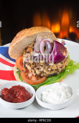 Hausgemachte Quorn Burger in einem sauerteig Brötchen mit Salat, Tomaten, roten Zwiebeln, serviert mit Ketchup und Soja Joghurt Dips. Stockfoto