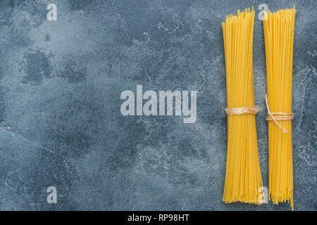 Rohe Makkaroni, Spaghetti auf einem dunklen Stein Tabelle mit kopieren. Hausgemachten italienischen Teigwaren Stockfoto