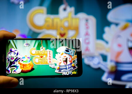 Los Angeles, Kalifornien, USA - 21. Februar 2019: Hände, die ein Smartphone mit Candy Crush SAGA Spiel gegen die großen Bildschirm. Stockfoto