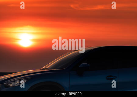 Blaue kompakte SUV-Auto mit Sport und modernes Design auf Beton durch das Meer geparkt bei Sonnenuntergang am Abend. Hybrid- und Elektroautos Technologie conc Stockfoto