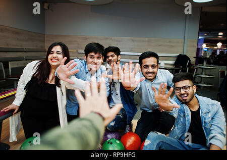 Gruppe von fünf asiatischen Völker in Ruhe und Spaß am Bowling Club. Holding bowling Bälle, sitzen auf der Gasse und die hohe fünf durch die Hände. Stockfoto