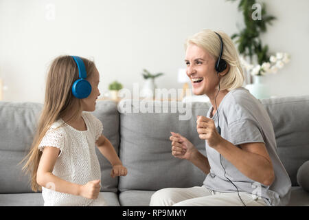 Aufgeregt Oma mit Enkelin im Kopfhörer Musik hören Stockfoto