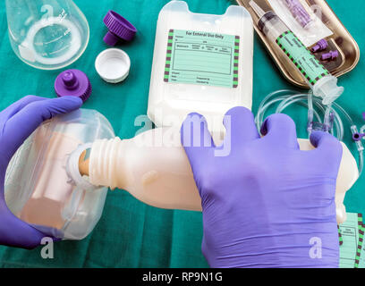 Krankenschwester Füllung Flasche Versorgung im Team der enteralen Ernährung, Palliativmedizin im Krankenhaus, konzeptionelle Bild, Komposition hotizontal Stockfoto